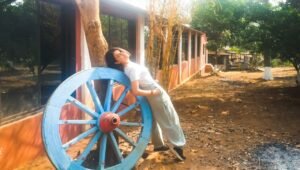 A girl leaning on a bullock cart wheel at our Karjat's Agro Farm House